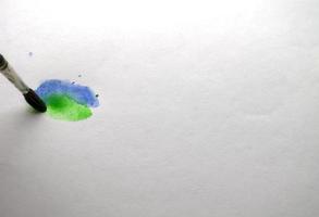 The brush draws blue and green paint. photo