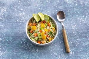 el arroz frito con coliflor de alimentos saludables tiene vegetales en un tazón blanco sobre una mesa de madera azul. foto