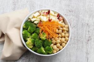 Healthy food broccoli salad add apple chickpeas in white bowl on wood background. photo