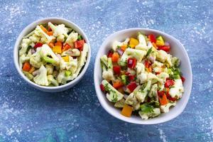 Ensalada de coliflor saludable en tazón blanco sobre fondo de madera azul. foto