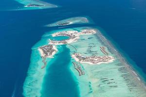 vista aérea de los arrecifes de coral en las islas maldivas. paisaje aéreo tropical. vacaciones de verano de lujo y destino de viaje foto