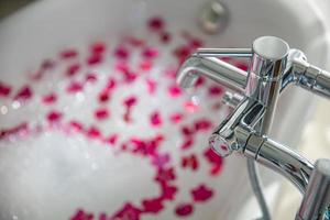 Blurred bath with foam and flowers. Romantic atmosphere, sunlight. Couple romance concept, surprise hot bath photo