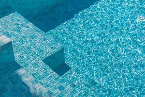 hermosa piscina de agua con relajantes destellos de sol en la superficie. vacaciones de verano o concepto de vacaciones, textura de piscina foto