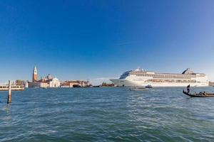 Big cruise ship with tourists leaving the city of Venice Italy on sunny day. Issue for the preservation of Venice fragile environment and city historic heritage photo