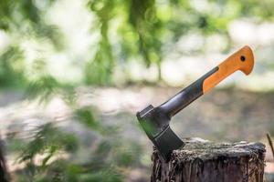 Axe in the stump. Modern axe tool impaled in log and fragments of alder wood behind it, hatchet tool splitting wood stumps and chopped logs lying on the ground, objects in horizontal orientation photo