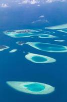 vista aérea de los arrecifes de coral en las islas maldivas. paisaje aéreo tropical. vacaciones de verano de lujo y destino de viaje foto