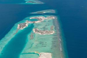 vista aérea de los arrecifes de coral en las islas maldivas. paisaje aéreo tropical. vacaciones de verano de lujo y destino de viaje foto