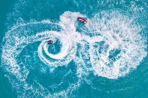 People are playing a jet ski in the sea. Aerial view. Top view.amazing nature background. Adventure and recreational sport activity in clear turquoise sea water at tropical beach. Summer sport fun