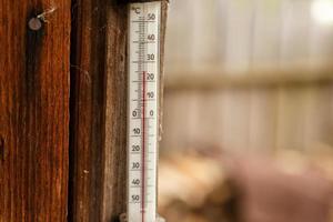 A street thermometer hangs on the wall of a wooden house. photo