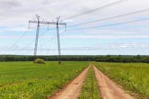 The road in the field near the power line. Beautiful landscape photo