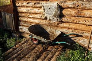 empty garden manure cart stands near the wall of the barn. photo