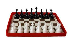 plastic chess board isolated on a white background. Travel chess. Selective focus. Focus on black pieces. photo