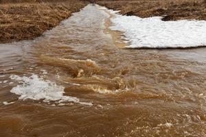 agua fangosa del río. corriente rápida con agua sucia durante el deshielo en primavera. foto