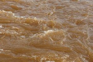 agua fangosa del río. río de primavera con agua fangosa marrón. fondo foto