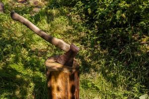 hacha clavada en el tocón. hacha con mango de madera en un tocón en el bosque. foto