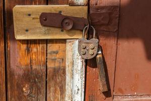 Vintage mechanical combination lock hanging on door. The door of the house is locked. photo