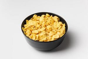 Corn flakes in dark bowl on white background. photo