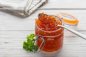 Red caviar in a jar with spoon photo