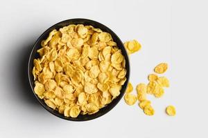 Corn flakes in dark bowl on white background. photo