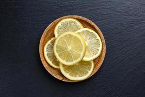 Lemons on wooden plate on dark stone background. photo