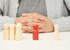 group of wooden figures, and one standing. Between them is a red wooden figurine of the negotiator man. Finding a compromise, discussion photo