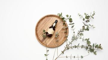 brown glass bottle with a pipette and an empty glued label on a wooden board, next to a branch of eucalyptus photo