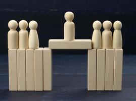 wooden men stand on the destroyed bridge on different sides on a blue background negotiator between them photo