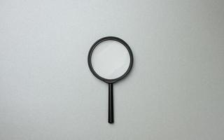 black magnifier on a gray background and question marks. The concept of uncertainty and the search for solutions photo