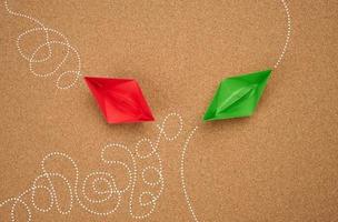 two paper boats with different trajectory on a brown background. The concept of optimal problem solving, achieving goals in different ways, smart and capable employee photo