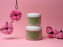 tarro verde para cosméticos sobre un fondo rosa. envases para crema, gel, suero, publicidad y promoción de productos