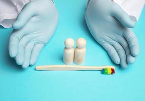 wooden figurines and hands of a doctor in medical blue gloves photo