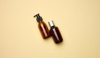 botellas de vidrio marrón con dispensador sobre fondo beige. envases para gel, suero, publicidad y promoción. productos orgánicos naturales. Bosquejo foto