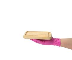 mano en guante de látex rosa sosteniendo una tabla de cortar rectangular sobre fondo blanco aislado foto