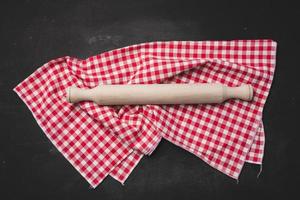 Old wooden rolling pin for rolling dough on a black background photo