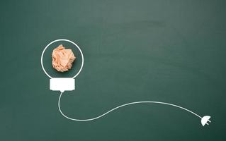 crumpled sheet of  paper on a green background, shape of a light bulb. Energy saving concept photo