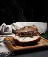 trozo de carne de cerdo al horno con especias sobre una tabla de madera, cortado en trozos. ojo de filete asado redondo foto