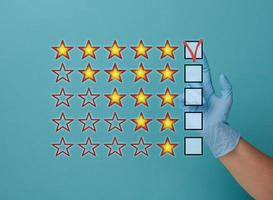 Evaluation and rating concept by voting. Best service and product. Hand in medical latex glove on blue background photo