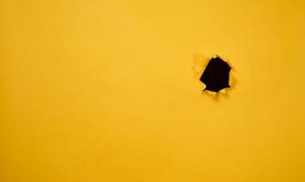 hole with torn edges in yellow paper, full frame. Copy space photo