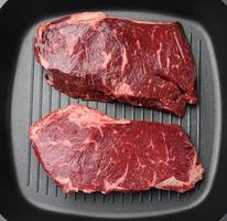 two raw pieces of beef in a black square grill pan photo