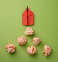 red paper airplane and crumpled paper balls on a green background, top view. The concept of finding innovative ideas photo