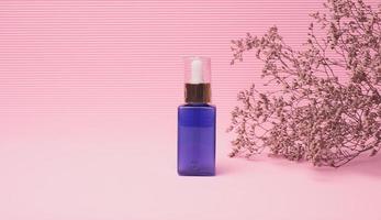 botella de vidrio azul con un cuentagotas para cosméticos sobre un fondo rosa. envases para gel, suero, publicidad y promoción. productos organicos naturales foto