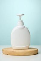 White plastic container with a pump for cosmetic liquid, liquid soap on the table photo