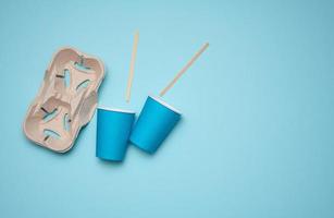disposable blue paper cups, wood sticks and paper tray on blue background. Takeaway beverage container, top view photo