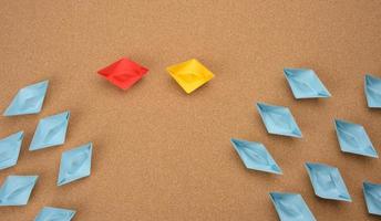 group of paper boats on a brown background. concept of a strong leader in a team, manipulation of the masses, following new perspectives photo