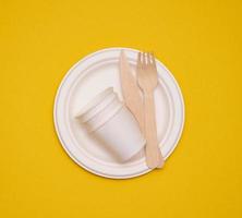 paper cups and plates on a yellow background. Recyclable garbage, rejection of plastic photo