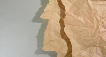 mint brown piece of paper with torn edges and shadow on gray background. Abstract creative backdrop for designer photo