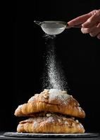 baked croissants on a black wooden board sprinkled with powdered sugar photo