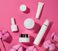 frasco y tubos de plástico blancos vacíos para cosméticos sobre un fondo rosa. envases para crema, gel, suero, publicidad y promoción de productos, vista superior foto