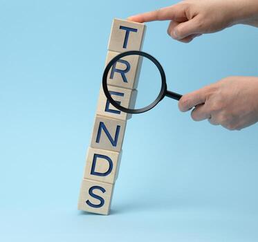 las manos están sacudiendo una lupa y cubos de madera con las tendencias de inscripción foto