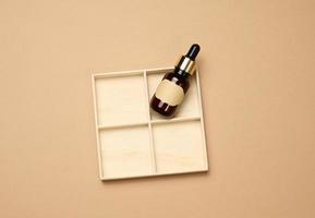 glass brown bottle with pipette a on light brown background. Mockup skincare cosmetic product photo